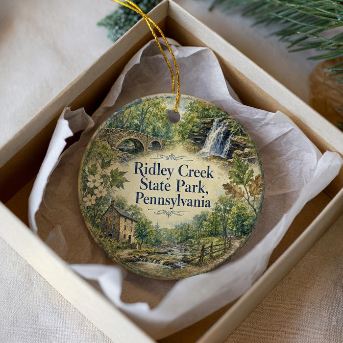 A decorative ornament in a box, featuring a scenic image of Ridley Creek State Park in Pennsylvania.