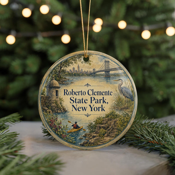 A round ornament with a painting of a park scene, featuring a bridge, a crane, and a person kayaking, hanging from a string.