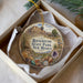A decorative ornament in a box, featuring an illustration of a desert landscape with mountains and a small building.