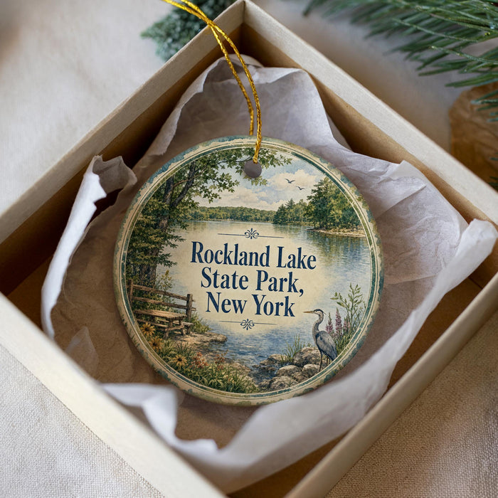 A round ornament in a box, featuring a scenic image of Rockland Lake State Park in New York.