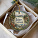 A decorative ornament in a box, featuring a scenic landscape with a house, trees, and a waterfall.