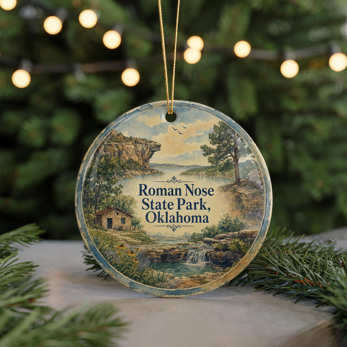 A round ornament with a painting of a scenic landscape, featuring a house, trees, and a waterfall, hanging from a string.