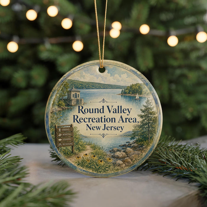 A round ornament with a scenic landscape of a lake, mountains, and a building, surrounded by greenery and a string of lights.
