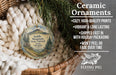 Ceramic ornaments, specifically a round ornament with a mountain landscape, are displayed in a basket with pine branches.