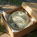 A decorative ornament in a brown box, featuring a scenic image of Sadlers Creek State Park in South Carolina.