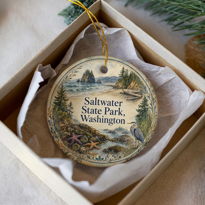 A decorative ornament in a white box, featuring a scenic landscape with a body of water, trees, and a bird.