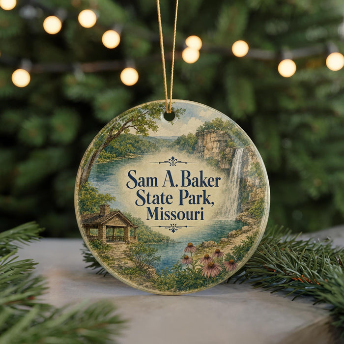 A round ornament with a scenic landscape featuring a waterfall, a cabin, and pine trees, with the text "Sam A. Baker State Park, Missouri" displayed on it.