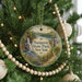 A round ornament hanging on a Christmas tree, featuring a scenic landscape with a waterfall and a gazebo.