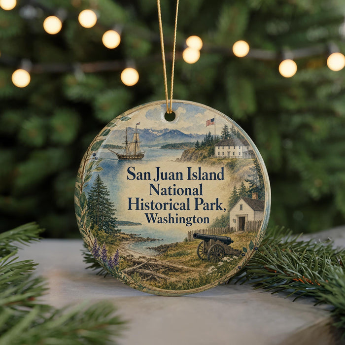 A round ornament with a painting of San Juan Island National Historical Park, Washington, featuring a ship, a cabin, and a landscape with mountains in the background.