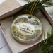 A round ornament with a scenic landscape of a mountain, river, and pine trees, along with the text "Schafer State Park, Washington".