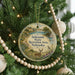 A round ornament hanging on a Christmas tree, featuring a scenic landscape with a deer, a bird, and a body of water.