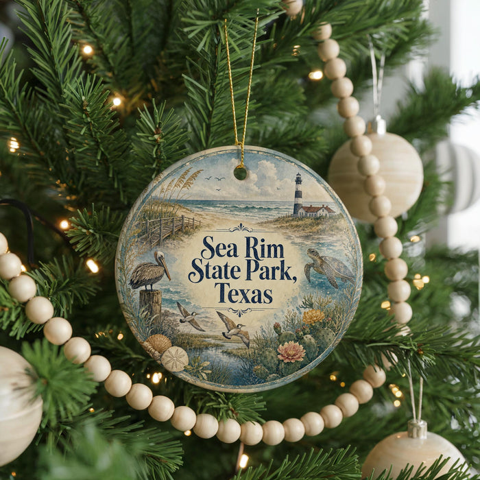 A round ornament hanging on a Christmas tree, featuring a lighthouse and a beach scene with birds and flowers.