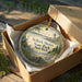 A decorative ornament in a box, featuring a scenic image of the Selkirk Shores State Park in New York.