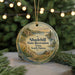 A round ornament with a scenic landscape featuring a lake, mountains, and a deer, hanging from a string.