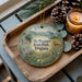 A decorative ornament featuring a scenic landscape of Sky Meadows State Park, Virginia, with a deer and pine cones on a wooden tray.