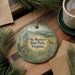 A decorative ornament featuring a scenic landscape of Sky Meadows State Park, Virginia, with a deer and other wildlife elements. The ornament is hanging on a wooden surface, surrounded by pine branches and a cup of coffee.