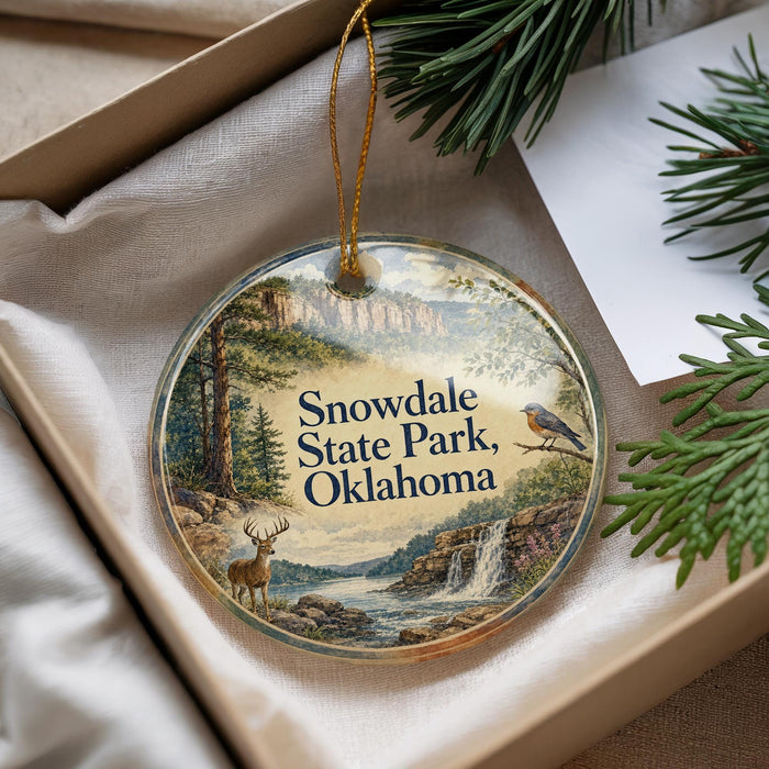 A decorative ornament with a scenic landscape of Snowdale State Park, Oklahoma, featuring a bird perched on a branch and a deer standing near a waterfall.