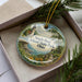 A decorative ornament with a lighthouse and a scenic landscape, featuring the text "South Bass Island State Park, Ohio".