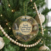 A round ornament hanging on a Christmas tree, featuring a scenic landscape with a waterfall and a bridge.