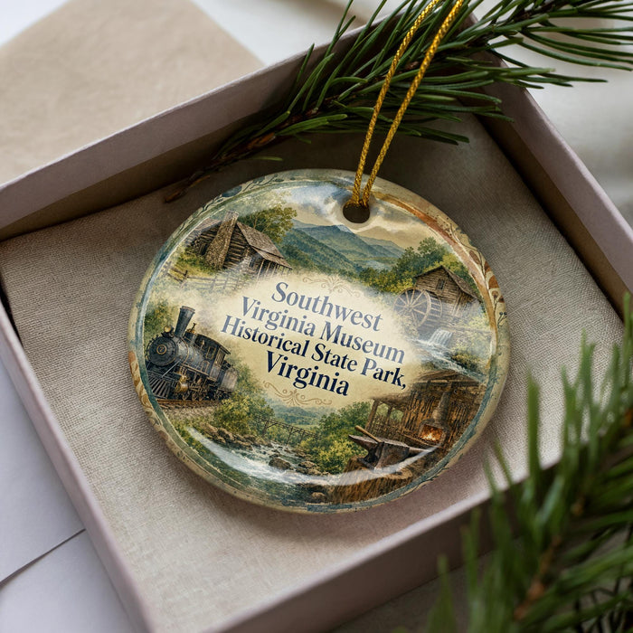 A decorative ornament in a box, featuring a scenic landscape with a train, buildings, and greenery.
