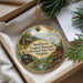 A decorative ornament with a scenic landscape featuring a train, a cabin, and a waterfall, placed inside a box with pine branches.