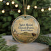 A circular ornament with a picture of a bison in a field, surrounded by pine branches and a string of lights in the background.