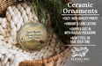 Ceramic ornaments, featuring a round ornament with a landscape scene and a buffalo, hanging in a basket with pine branches.