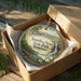 A decorative ornament in a wooden box, featuring a scenic landscape with a waterfall and flowers, with the text "Stand Stone State Park, Tennessee" printed on it.