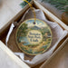 A round ornament with a scenic landscape of Steinaker State Park, Utah, displayed in a box with a white tissue paper lining.