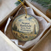 A round ornament with a painting of a rural landscape, featuring a tall monument, is displayed in a box.