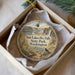 A decorative ornament in a box, featuring a scenic landscape with a waterfall and a bird perched on a rock.