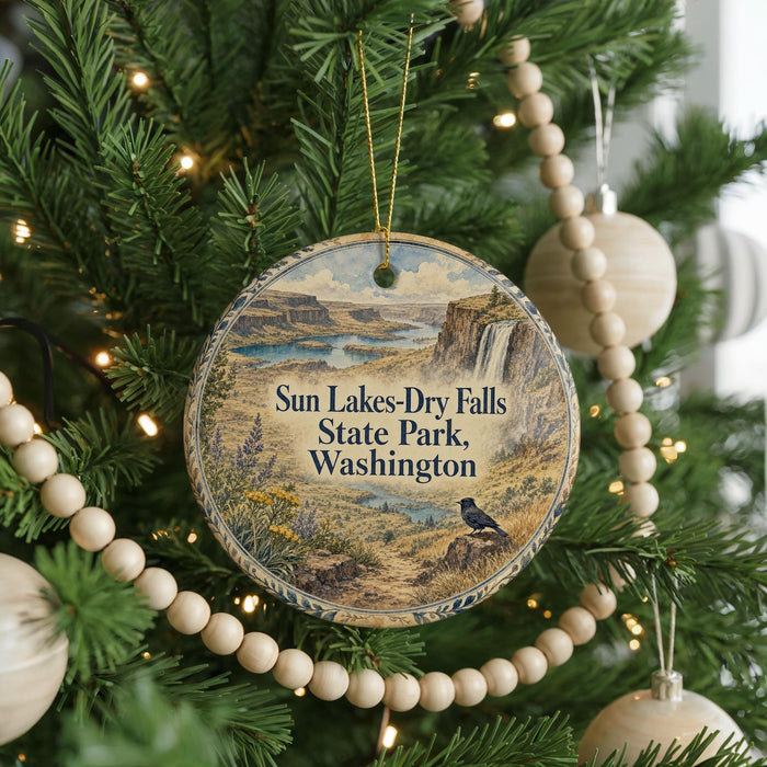 A circular ornament hanging on a Christmas tree, featuring a scenic landscape with a waterfall and a bird perched on a rock.