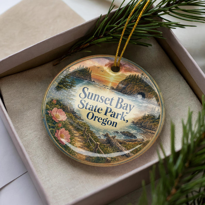 A decorative ornament with a scenic landscape of Sunset Bay State Park, Oregon, featuring a sunset over the water and pine trees.