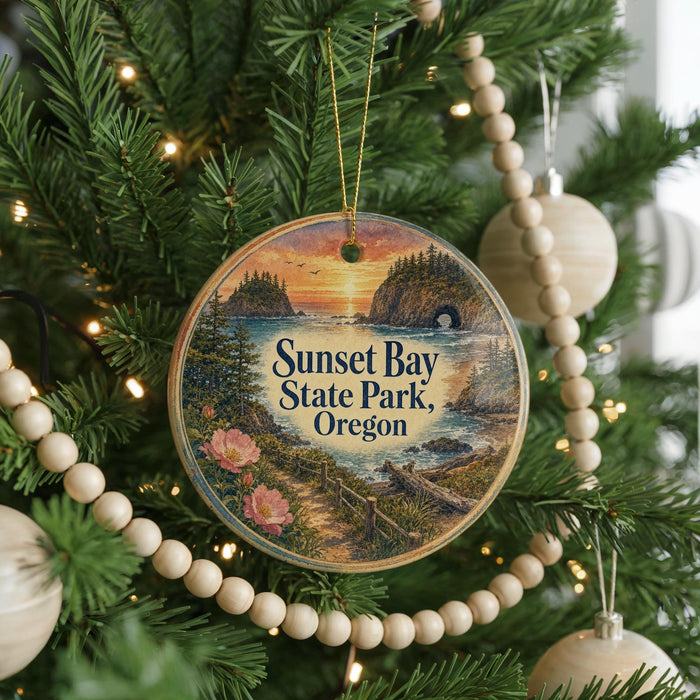 A round ornament hanging on a Christmas tree, featuring a scenic landscape with a sunset over a body of water and a forested area.