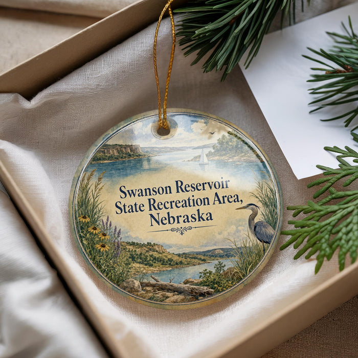 A decorative ornament with a scenic landscape of a lake, mountains, and a bird, hanging from a string.