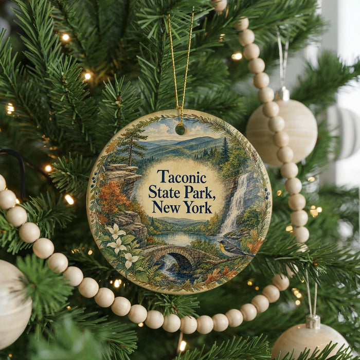 A round ornament hanging on a Christmas tree, featuring a scenic landscape with a waterfall and a bridge.