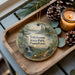 A wooden tray with a decorative ornament featuring a scenic landscape of Tobyhanna State Park, Pennsylvania, and pine cones.