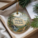 A round ornament with a scenic landscape of trees, water, and a waterfall, hanging from a string.
