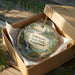 A decorative ornament in a brown box, featuring a scenic landscape with a waterfall and pine trees, with the text "Tobhanna State Park, Pennsylvania" printed on it.