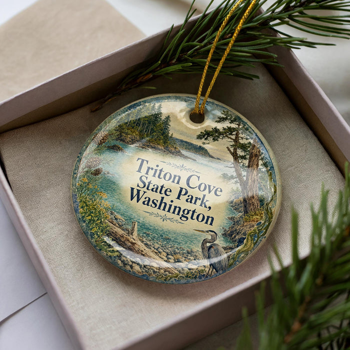 A decorative ornament in a box, featuring a scenic landscape with a body of water, trees, and a bird.