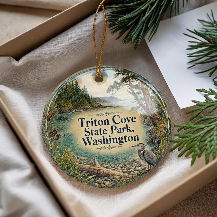A decorative ornament in a box, featuring a scenic landscape with a bird and trees, along with the text "Triton Cove State Park, Washington".