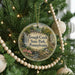 A round ornament hanging on a Christmas tree, featuring a scenic image of a waterfall and a bird.