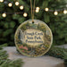 A round ornament with a scenic image of a waterfall and a bird, surrounded by greenery, is hanging from a string.