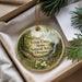 A round ornament with a scenic forest landscape and a waterfall, hanging from a string.