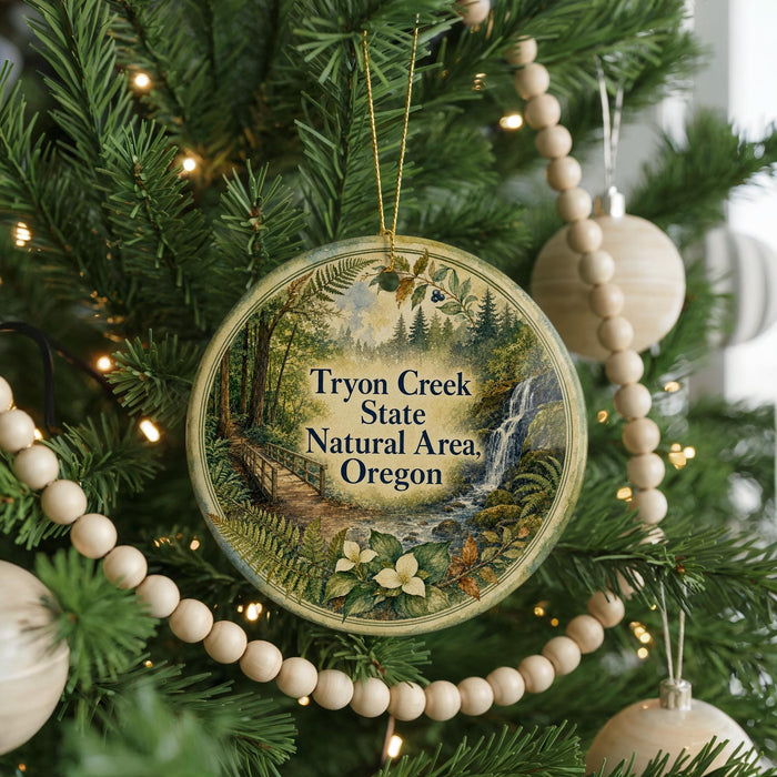 A circular ornament hanging on a Christmas tree, featuring a scenic image of a forest and a waterfall.