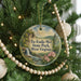 A round ornament hanging on a Christmas tree, featuring a scenic landscape with a waterfall and mountains.