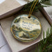 A decorative ornament in a box, featuring a turtle and a scenic landscape, with the text "Turtle River State Park, North Dakota" printed on it.