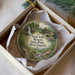 A decorative ornament in a white box, featuring a scenic image of Twin Falls Resort State Park, West Virginia.