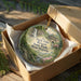 A decorative ornament in a wooden box, featuring a scenic image of Twin Falls Resort State Park West Virginia.