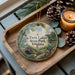 A decorative ornament featuring a scenic image of Twin Lakes State Park, Virginia, with a candle and pine cones on a wooden tray.